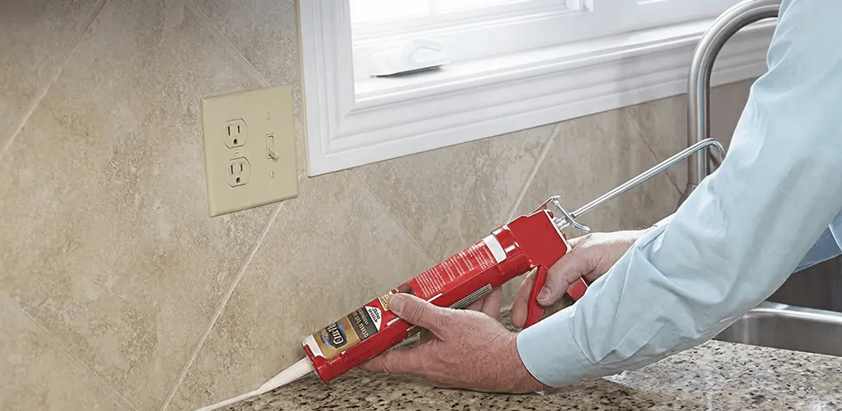Handyman applying caulk along a kitchen backsplash and countertop seam in Raleigh, NC